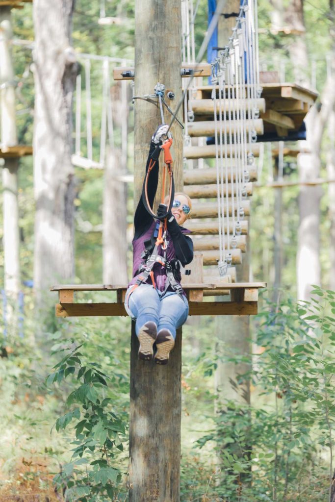 Woman ziplining and smiling on our aerial adventure park