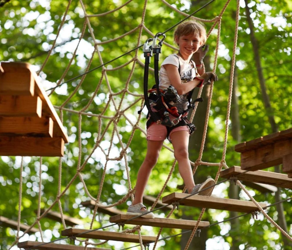 smiling girl on spider web element at aerial adventure park