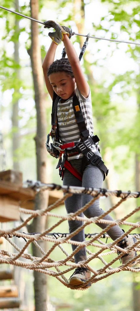 Girl going through treetop obstacles at Boundless Adventures.
