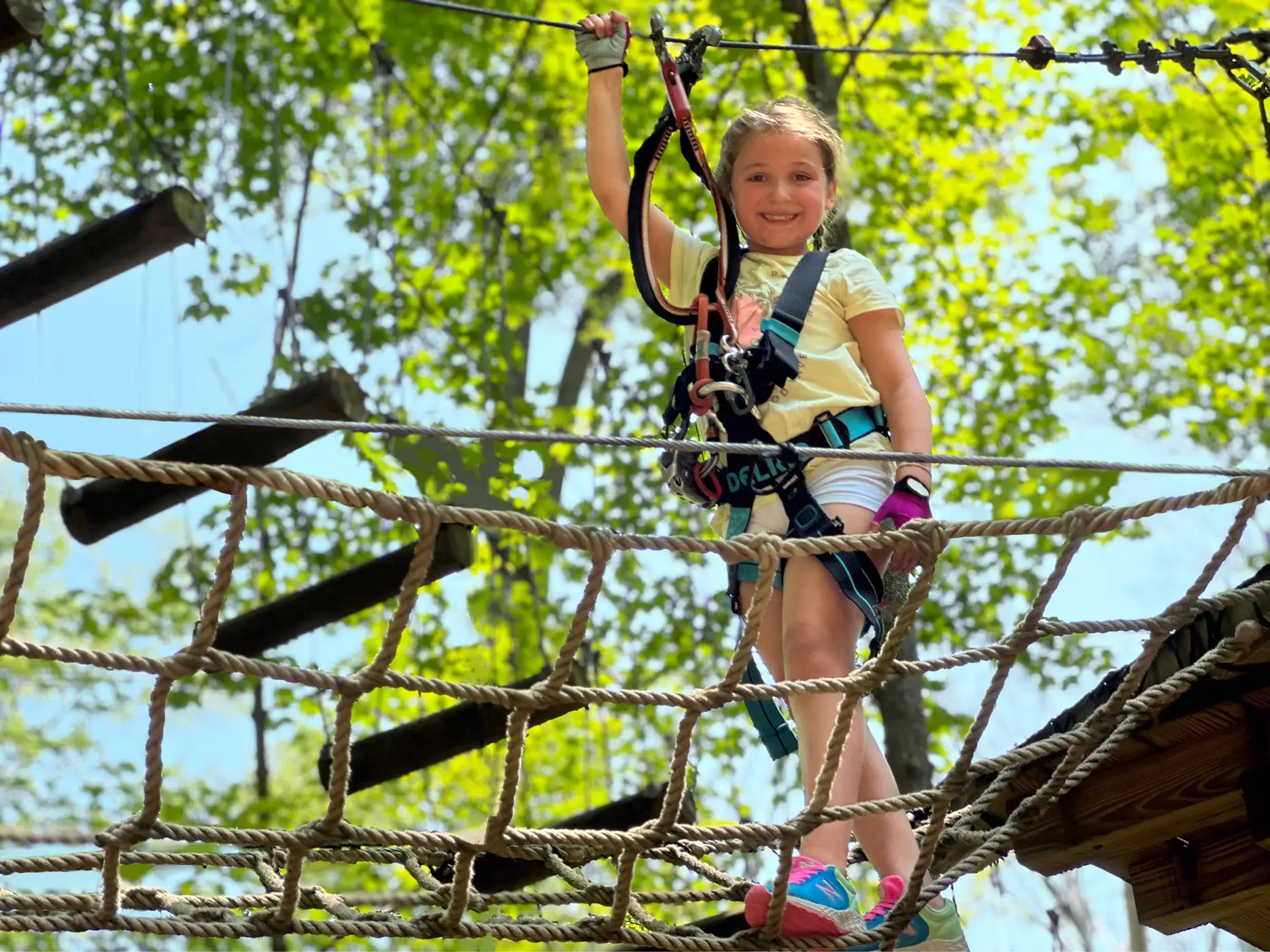 Young child on cargo net tree top obstacle